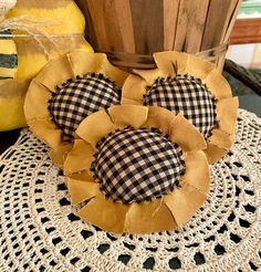 two decorative sunflowers sitting on top of a doily next to a basket