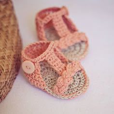 a pair of crocheted baby shoes sitting next to a straw hat on a white surface