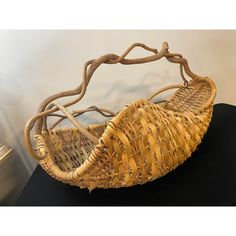 a wicker basket sitting on top of a black table next to a white wall