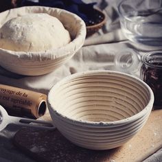 a bowl with dough in it sitting on a table next to other bowls and utensils