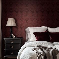 a bedroom with red wallpaper, white bedding and two lamps on nightstands