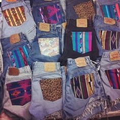 several pairs of jeans with different colored patches and designs on them, all stacked together