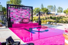 a stage set up with pink carpet and chairs in front of it on the sidewalk