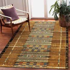 a large rug in the middle of a room with a chair and potted plant