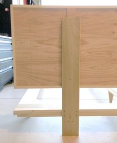 a wooden frame sitting on top of a white floor next to some drawers and cabinets