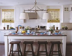 a kitchen island with three stools in front of it and plates on the counter