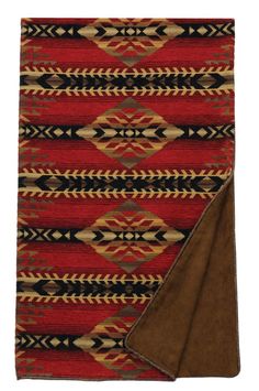 a red, black and tan rug with an area rug underneath it that has a brown blanket on top