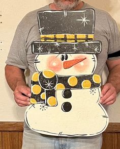 a man holding up a snowman cutout in front of his face