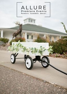 a white wagon with flowers on it sitting in front of a house and a horse statue