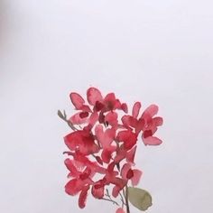 a vase filled with pink flowers on top of a wooden table next to a white wall