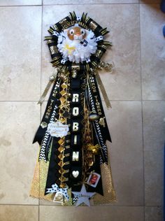 a black and gold ribbon on the floor with other items attached to it, including a teddy bear