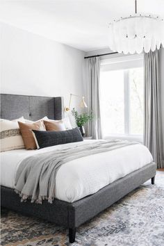 a bedroom with a large bed and chandelier hanging from it's ceiling