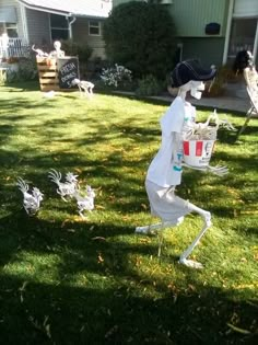 a scarecrow carrying a bucket full of food on his back in the yard next to some fake chickens