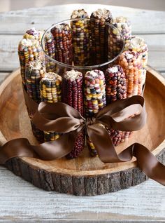 an arrangement of candy corn on a wooden platter with a ribbon tied around it