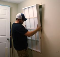 a man in a hat is opening the door to a room that has white walls