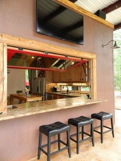 a screen shot of a kitchen with three stools in front of the counter and tv above it