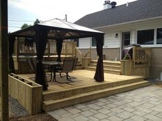 a gazebo sitting on top of a wooden deck next to a table and chairs