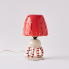 a red and white table lamp with an octopus on it's legs attached to a cord