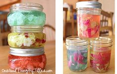 four jars filled with different colored confetti sitting on top of a wooden table