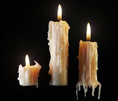 three candles with melting wax on them against a black background