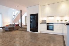 a living room filled with furniture next to a kitchen and dining room table in front of a staircase