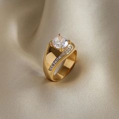 a gold ring with two diamonds on the top and bottom, sitting on a white cloth