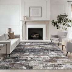 a living room with white furniture and a large rug on the floor in front of a fireplace