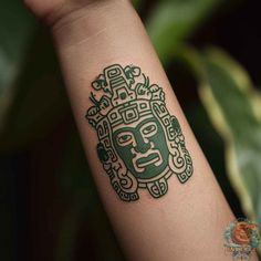 a tattoo on the arm of a person with a green face and ornate designs around it