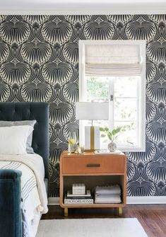 a bedroom with blue and white wallpaper and a bed in front of a window