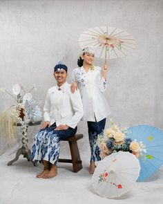 two people sitting on a bench with umbrellas in front of them and one person holding an umbrella