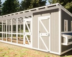 a small gray and white shed sitting on top of a grass covered field next to trees