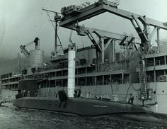 an old black and white photo of a boat in the water near a large ship