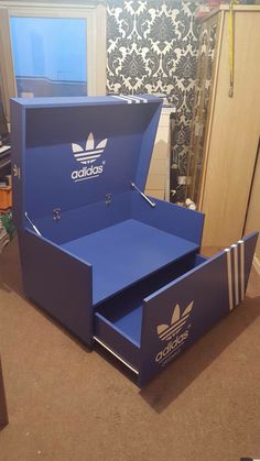 an open adidas shoe box sitting on the floor in a room with a wallpapered background