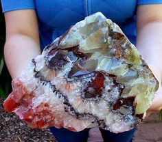 a person holding a piece of rock in their hands with other rocks and stones surrounding it