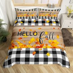 a bed covered in plaid and yellow leaves with hello fall written on the comforter