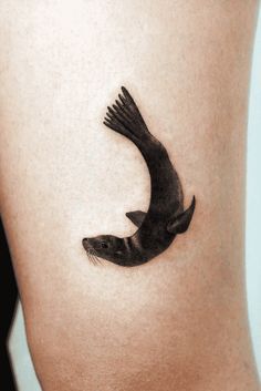 a small bird tattoo on the side of a woman's thigh, it appears to be flying through the air