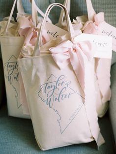 three bags with pink bows are sitting on a couch