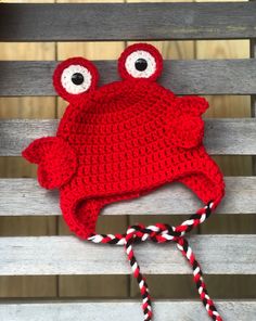 a red crocheted hat with eyes and a rope on it sitting on a bench