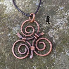 a copper pendant on a leather cord with an intricate design in the shape of three spirals