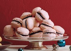 a glass plate filled with cookies on top of a table next to christmas balls and ornaments