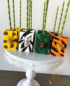 four small purses with zebra, giraffe and monkey designs on them sitting on a cake stand