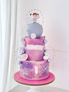 a three tiered cake decorated with pink and purple frosting, stars and decorations