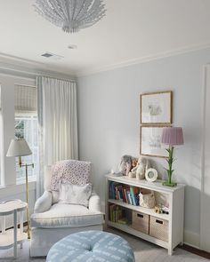 a living room filled with furniture and a white book shelf under a chandelier