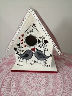 a white birdhouse with two birds on it's roof and the words home written in black