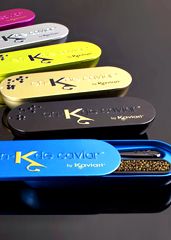 four different colored luggage tags sitting on top of each other in front of a black table