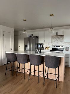 a kitchen with three bar stools next to an island in the middle of it