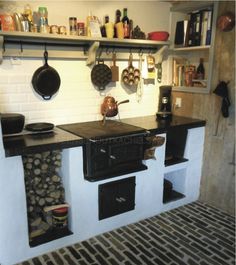 a stove top oven sitting inside of a kitchen next to a shelf filled with pots and pans