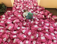 a pile of pink bags sitting on top of a floor next to a woman laying on the ground