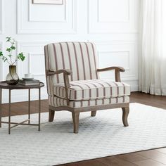 a striped chair sitting on top of a white rug next to a table with a vase