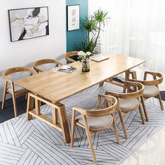 a dining room table with chairs and a vase on the floor in front of it